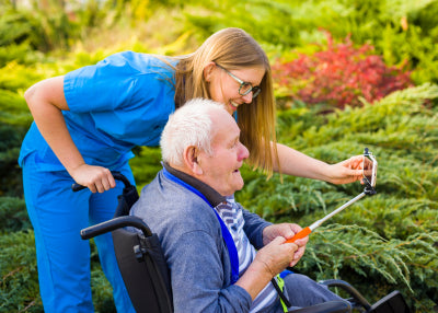 old woman sitting on her wheelchair with her caregivers